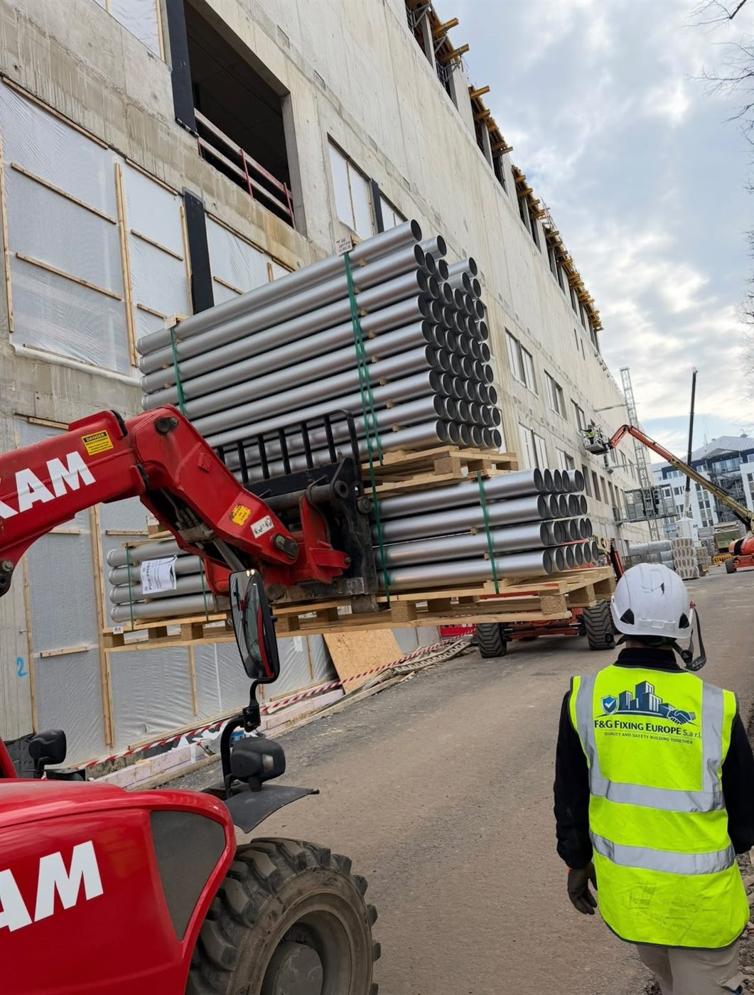 F&G Fixing Europe operative directing a telehandler lifting façade components on site
