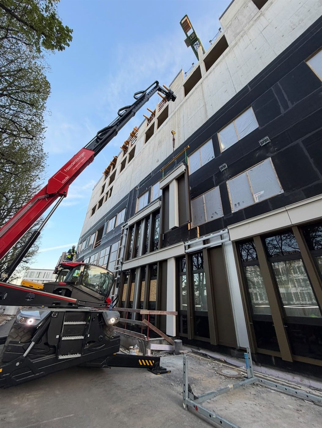Spider crane installing a façade panel on a glazed building