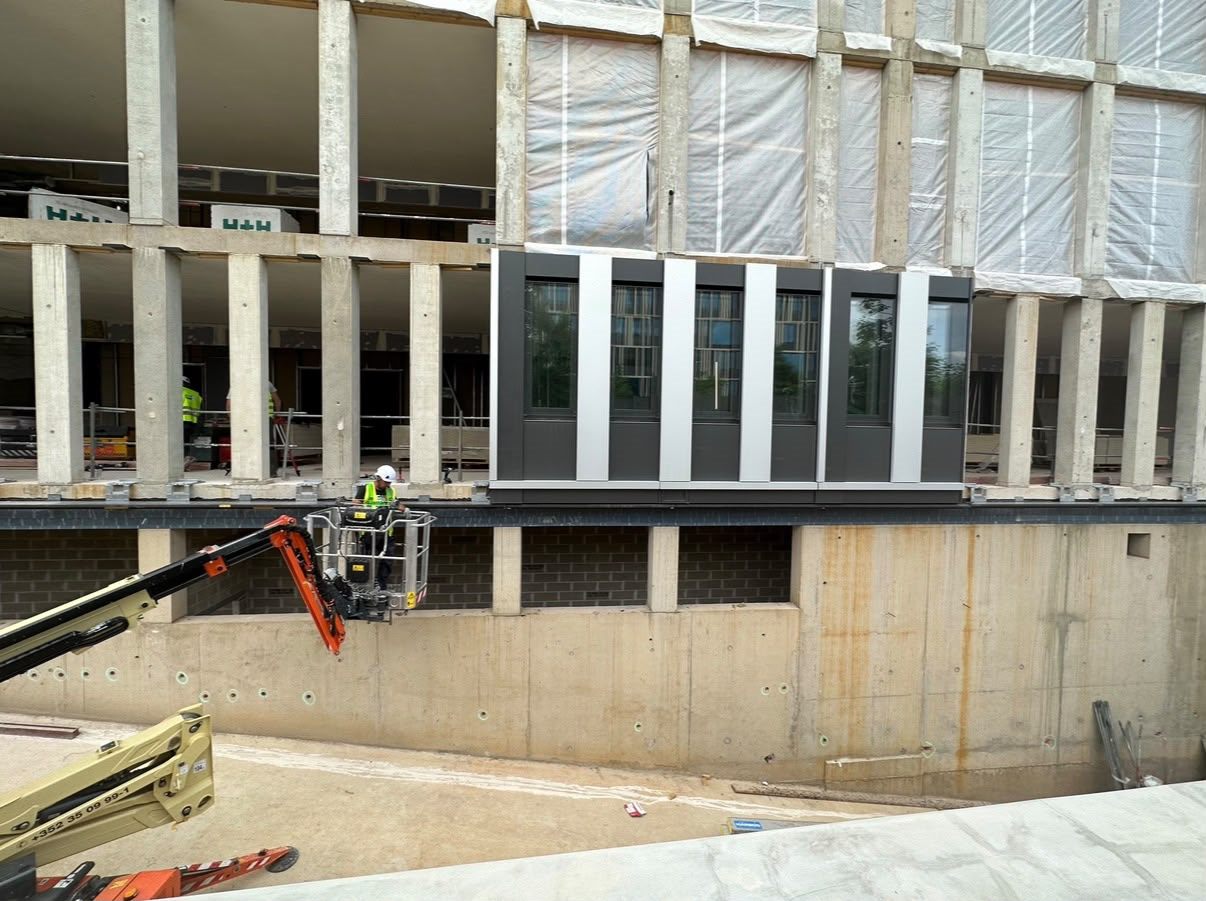 Dark rainscreen panels being installed from an access platform